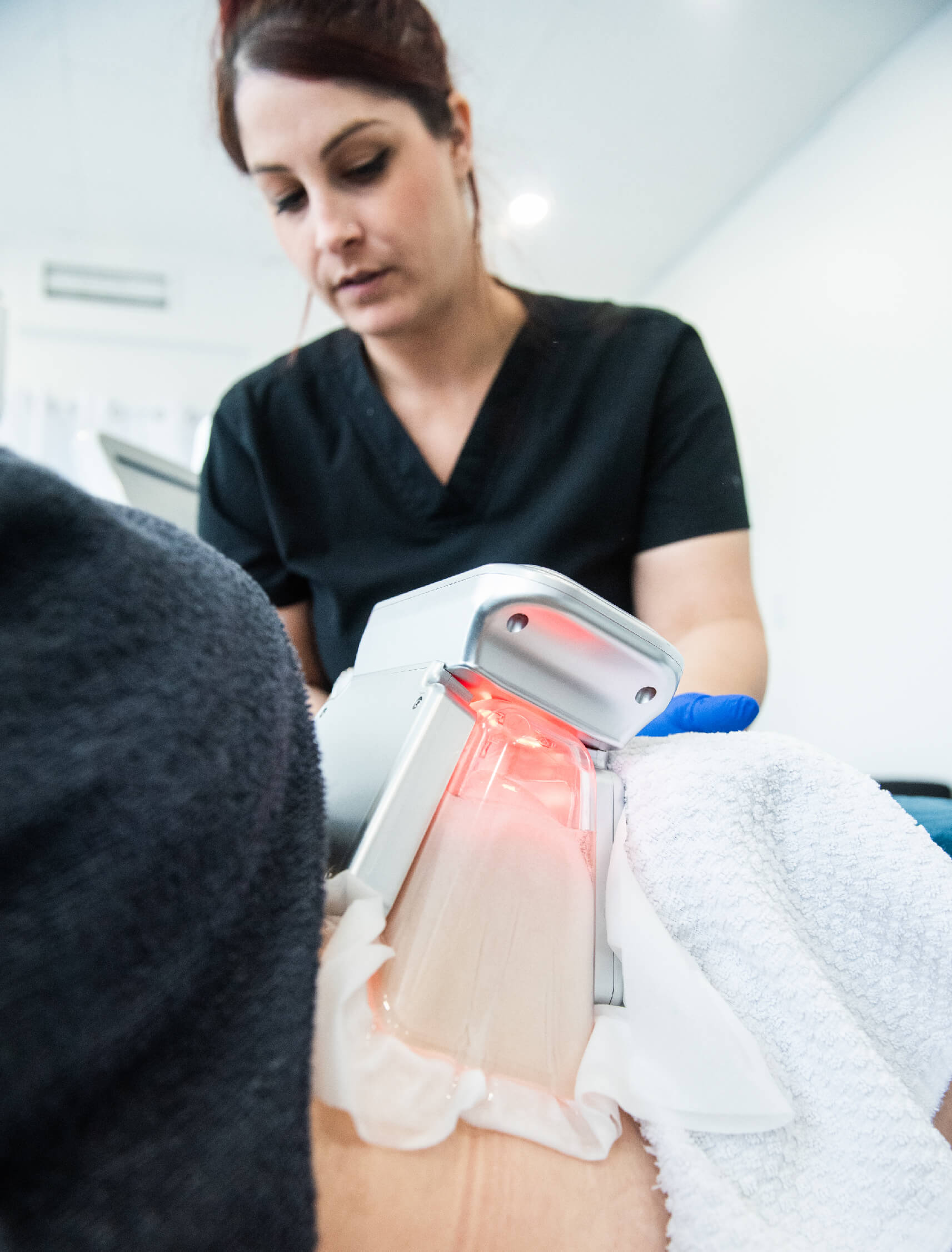 Professionnel de l’esthétique appliquant un appareil de cryolipolyse ColdSculpting sur un client, traitement de réduction des graisses ciblées avec lumière rouge indiquant l’activation de l’appareil