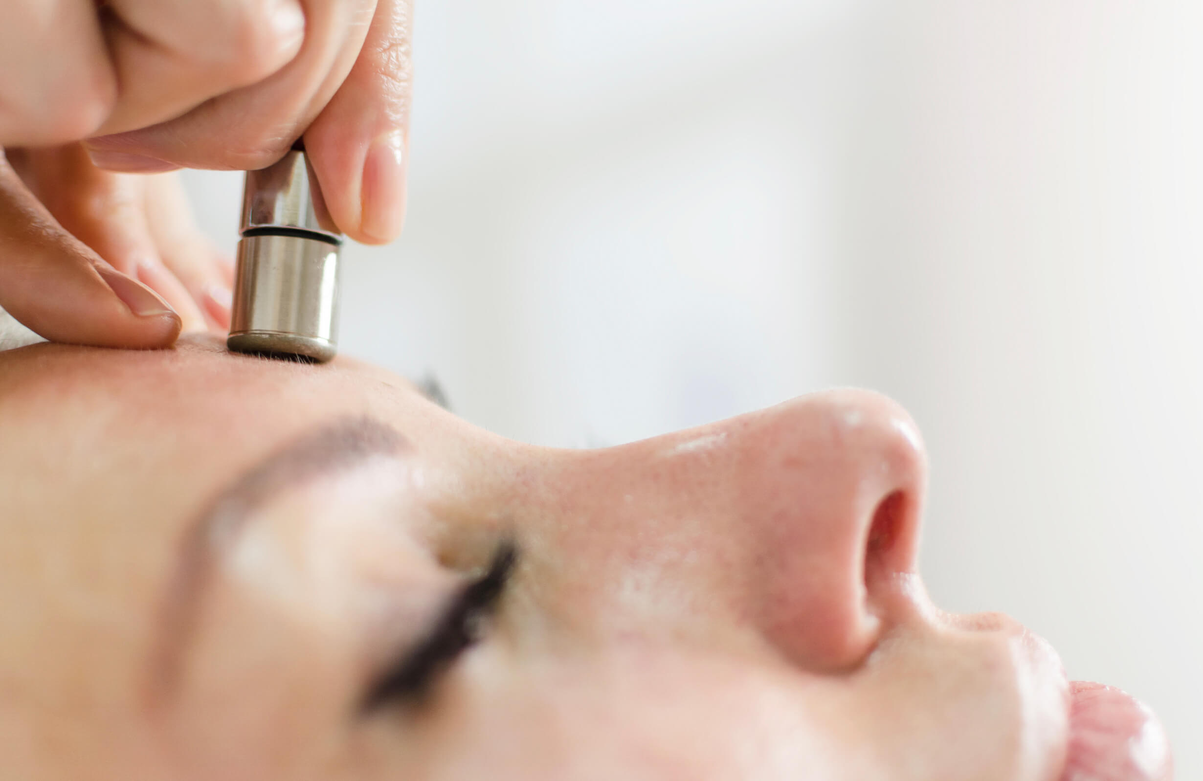 Soin de microdermabrasion en cours sur le front d’une cliente, offrant une exfoliation précise pour une peau éclatante et renouvelée