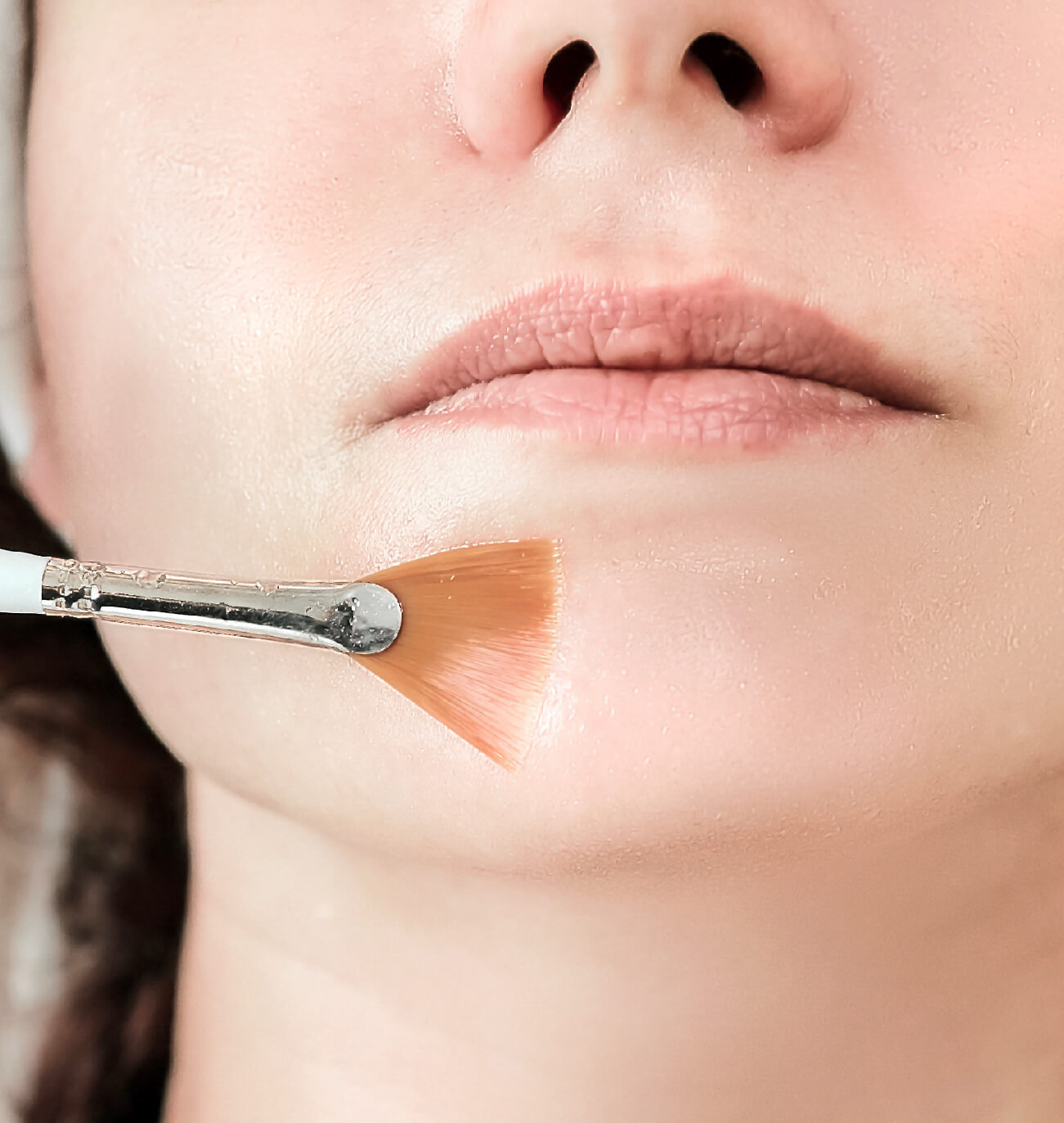 Zoom sur l’application d’un peeling glycolique au pinceau pour une exfoliation douce et ciblée sur le menton. Idéal pour affiner le grain de peau et illuminer le teint