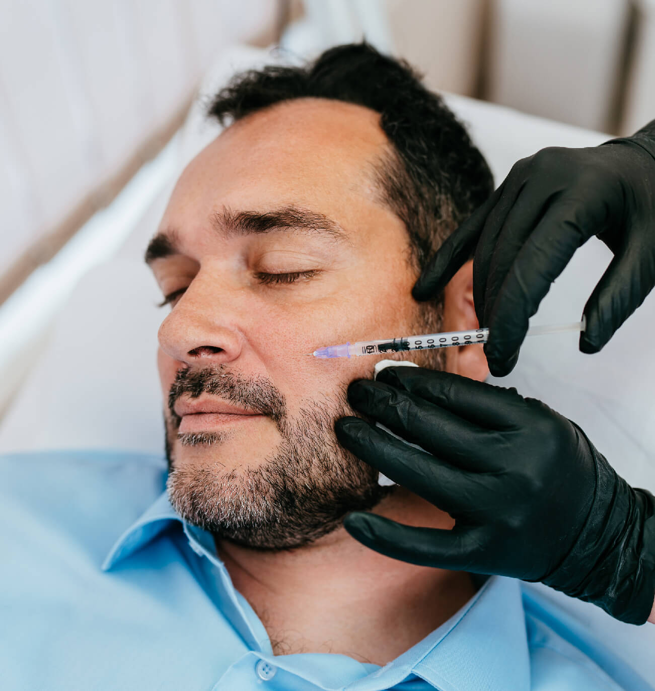 Homme recevant une injection esthétique au visage, mettant en avant un traitement pour revitaliser la peau, restaurer les volumes et améliorer l’apparence naturelle tout en ciblant des besoins spécifiques en clinique spécialisée